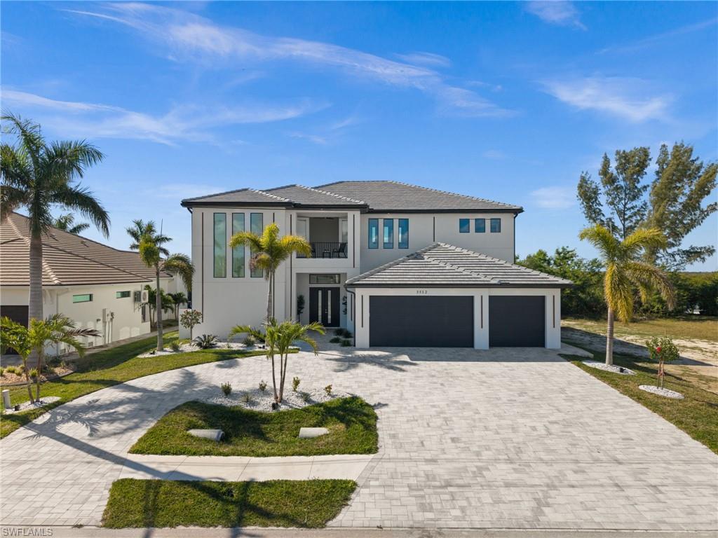 Image 3: View of front facade featuring driveway, a garage, a balcony, a front lawn, and stucco siding
