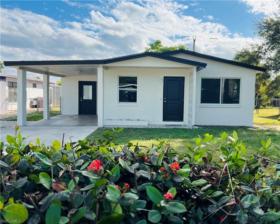 Image 1: View of front of property with stucco siding, a carport, and a patio area