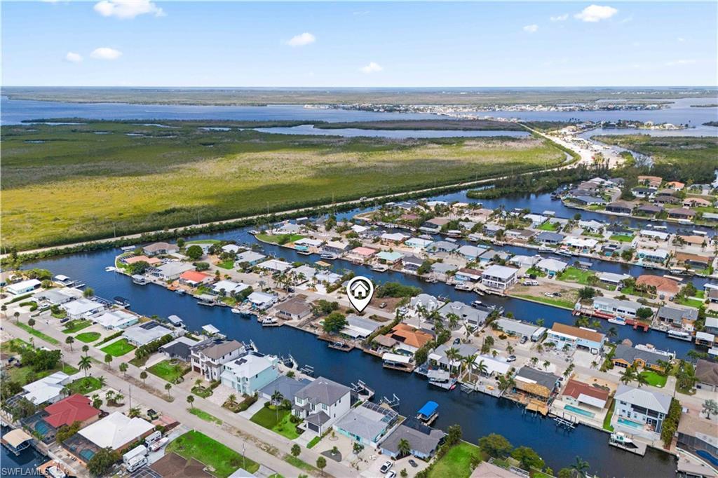 Image 2: The expansive aerial view highlights the generous lot size, with the home at the center, the pool as a focal point, and the dock offering quick access to the canal to open water.