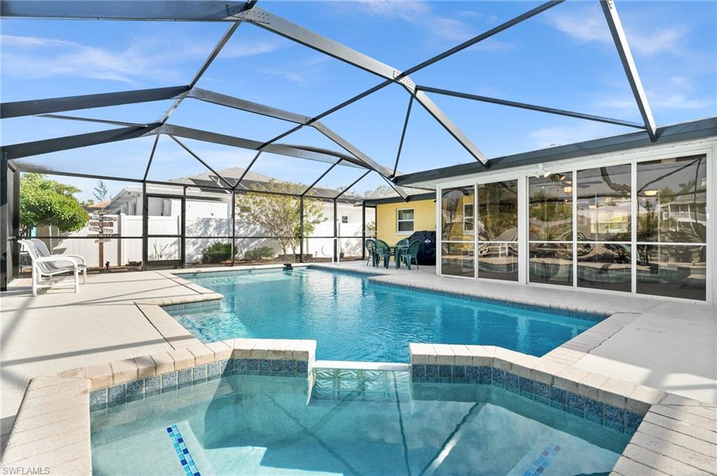 Image 3: View of swimming pool featuring a pool with connected hot tub, a sunroom, glass enclosure, and a patio area