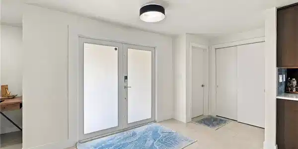 Image 3: Double-door entry with frosted glass panels, flush mount ceiling lighting, and light-toned tile flooring