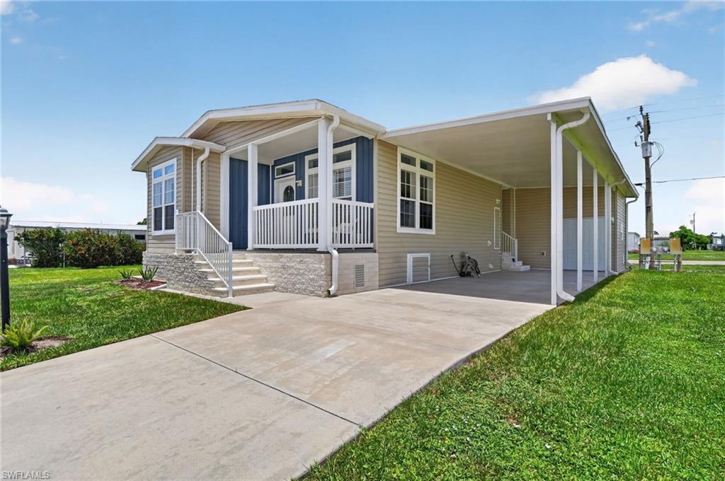 Image 2: Single-story residence featuring light tan siding with a contrasting blue accent wall on the front porch