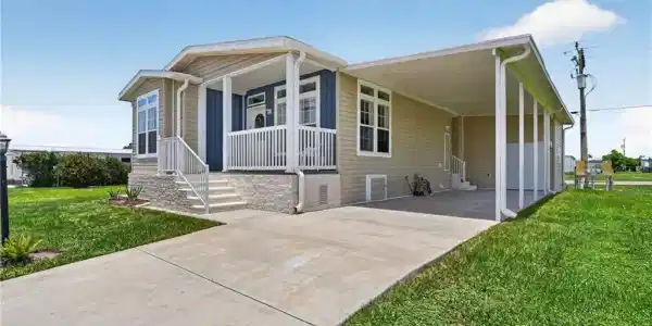 Image 2: Single-story residence featuring light tan siding with a contrasting blue accent wall on the front porch