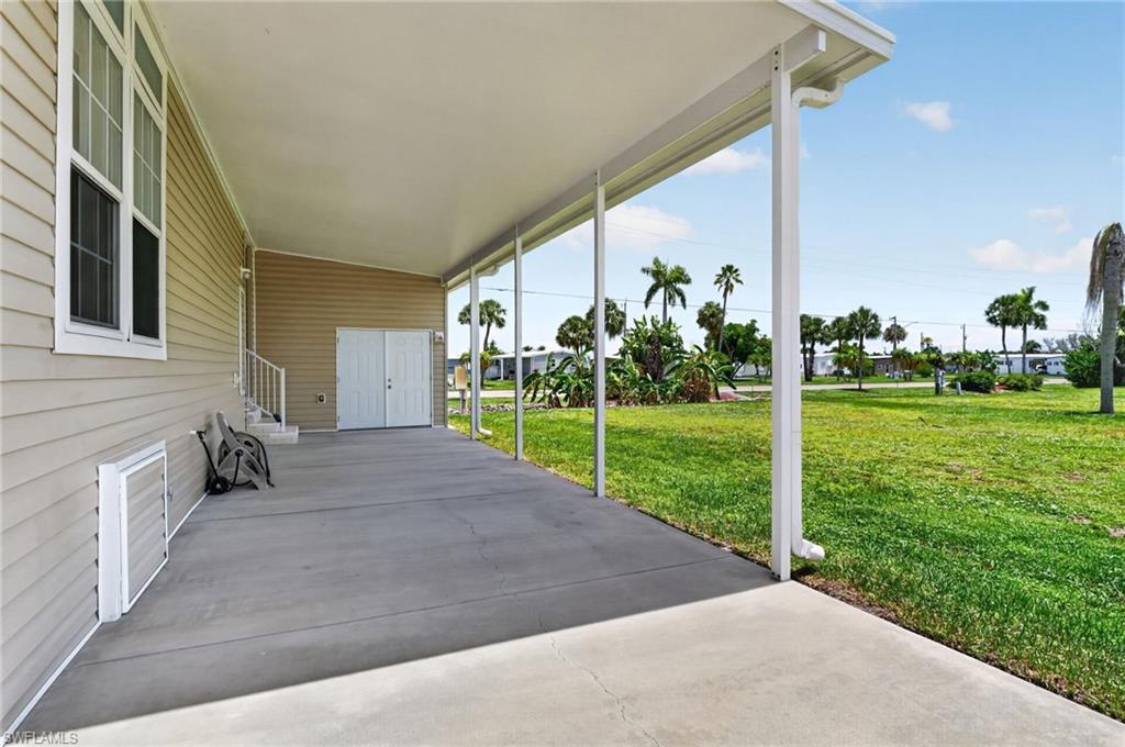 Image 3: Expansive covered patio with concrete flooring, supported by white posts, and featuring a light-toned vinyl siding exterior