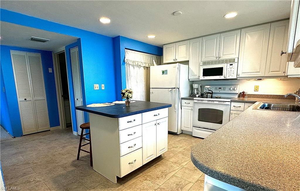 Image 4: Kitchen with sink, light tile patterned flooring, white cabinets, and white appliances