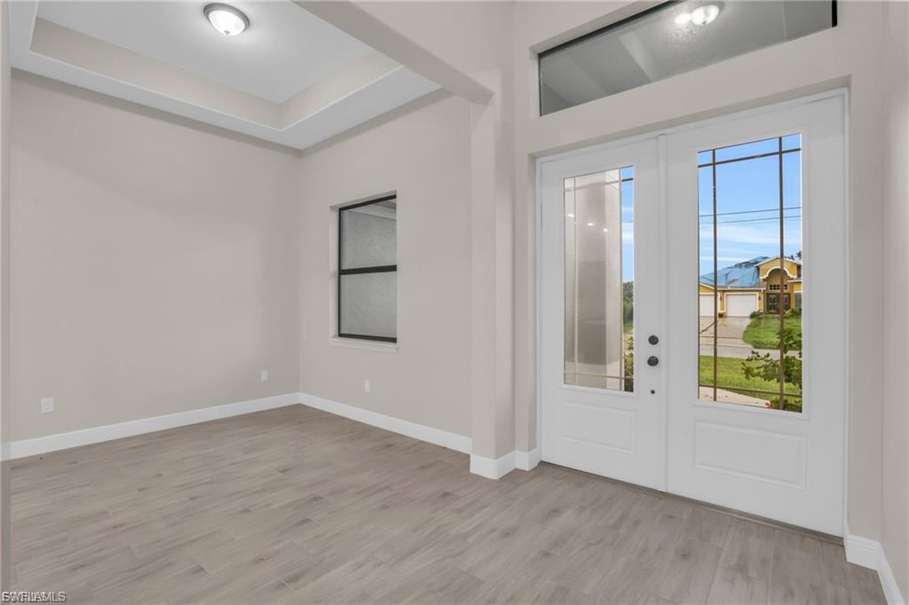 Image 3: Foyer entrance with light wood-type flooring, french doors, and a tray ceiling