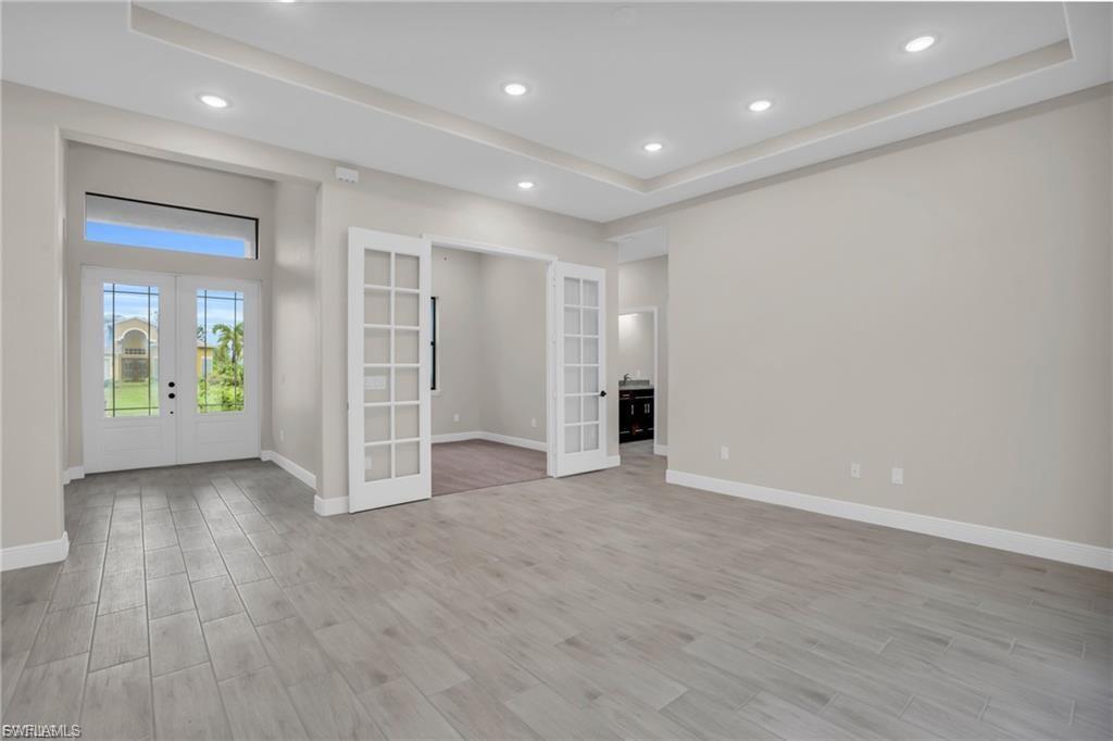 Image 4: Unfurnished room with french doors, a raised ceiling, light wood-style floors, and recessed lighting