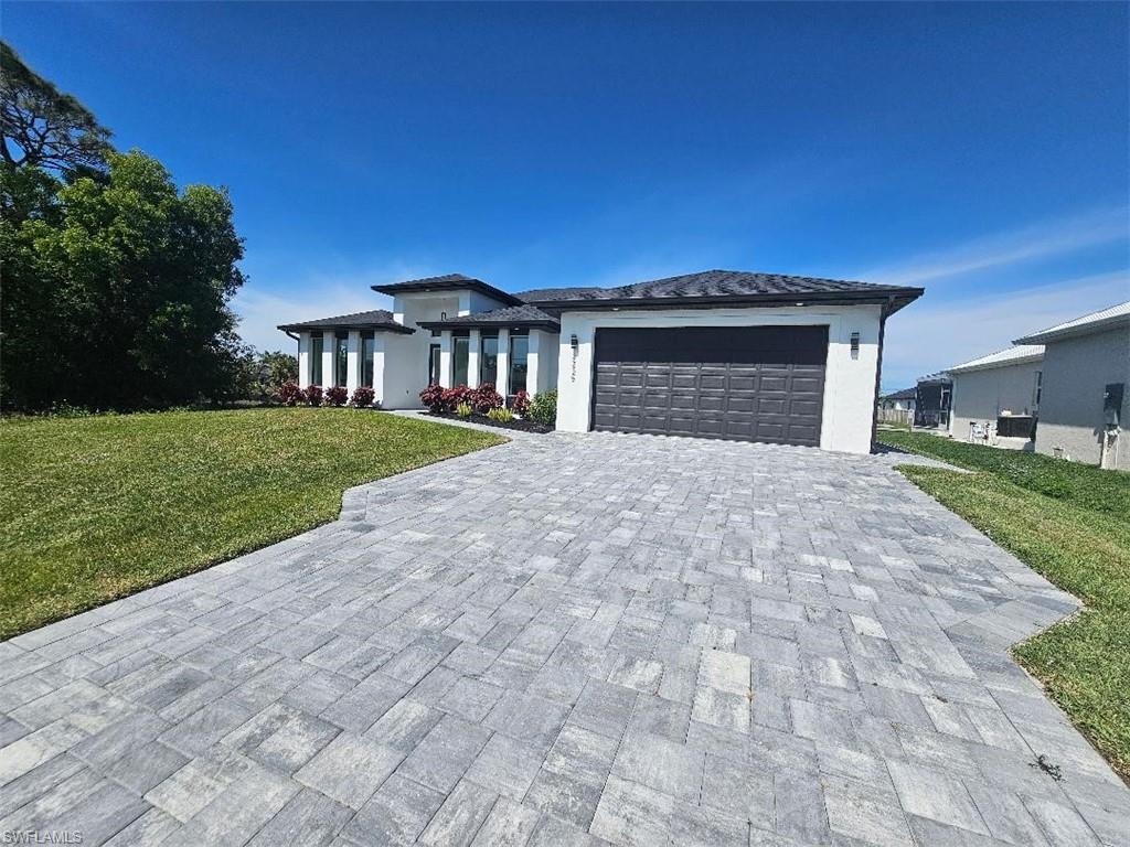 Image 1: Prairie-style home featuring a garage, a front lawn, decorative driveway, and stucco siding