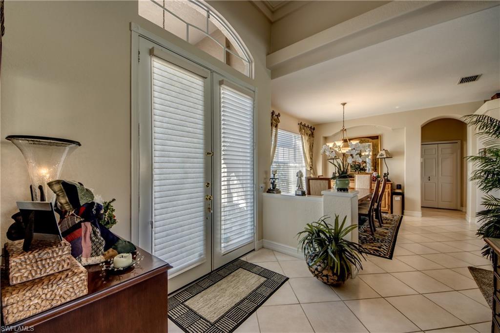 Image 3: Entrance foyer featuring french doors, arched walkways, light tile patterned floors, and suspended lighting