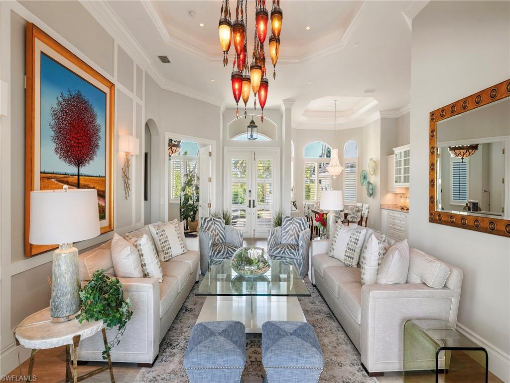 Image 4: Living area with a raised ceiling, french doors, arched walkways, crown molding, and wood finished floors