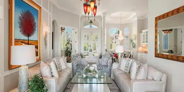 Image 4: Living area with a raised ceiling, french doors, arched walkways, crown molding, and wood finished floors