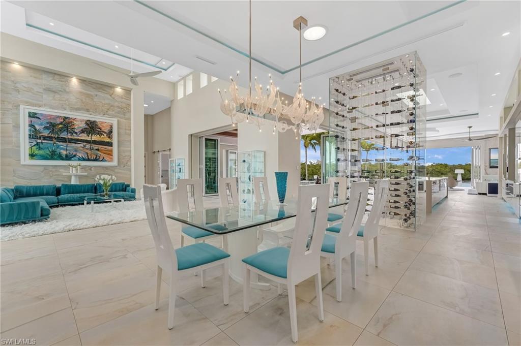 Image 2: This bespoke residence offers an open, flowing design where the formal living room transitions seamlessly into the dining area, creating an elegant sense of continuity throughout the main living spaces. A striking temperature-controlled wine cellar, enclosed in seamless glass and accommodating over 250 bottles, serves as a sophisticated architectural divider, beautifully separating the living and dining areas from the expansive kitchen.