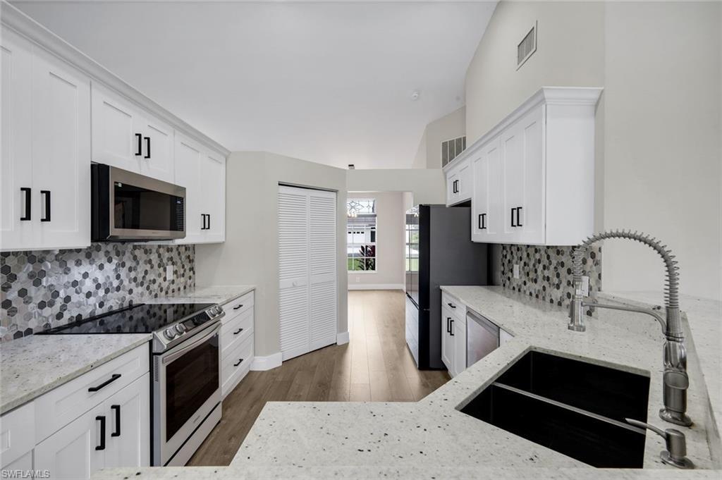 Image 3: Kitchen featuring white shaker cabinetry, speckled countertops, a mosaic tile backsplash, Samsung Stainless Steel Appliances, Quartz Countertops