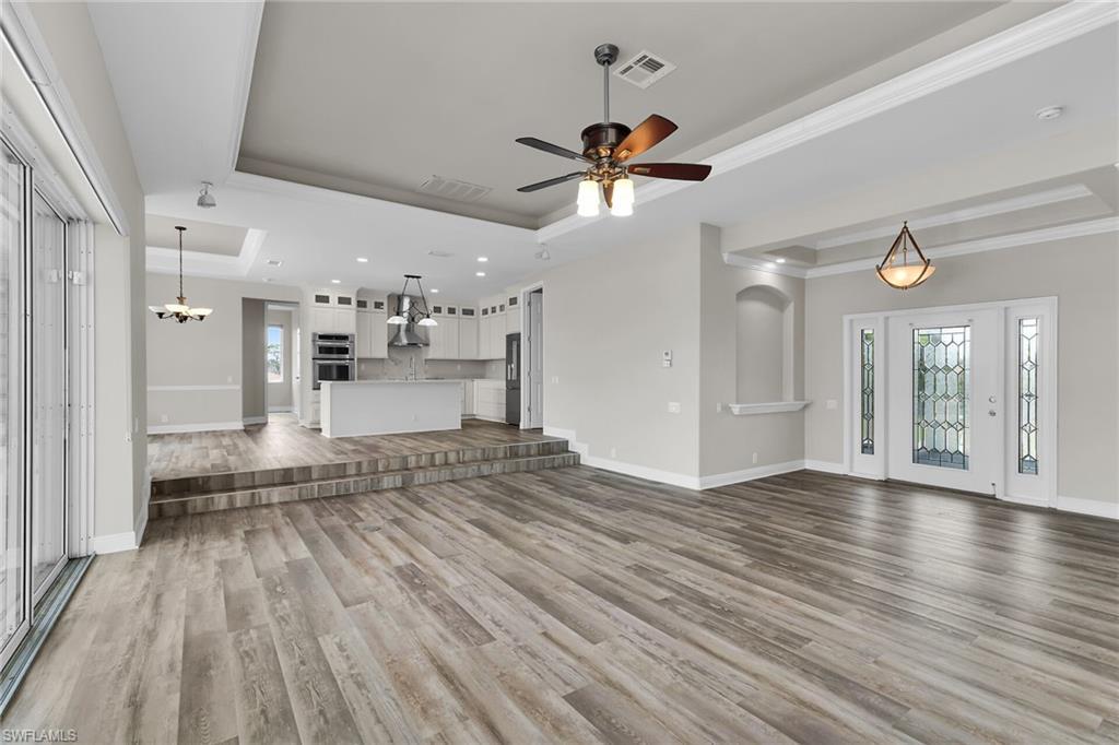 Image 2: Unfurnished living room featuring a raised ceiling, wood finished floors, ornamental molding, ceiling fan, and recessed lighting