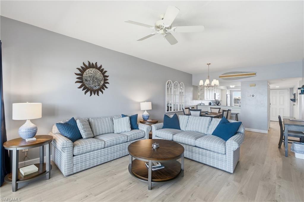 Image 3: Open-concept living area featuring light wood-finish flooring, a vaulted ceiling with a ceiling fan, and recessed lighting - Virtually Edited Image