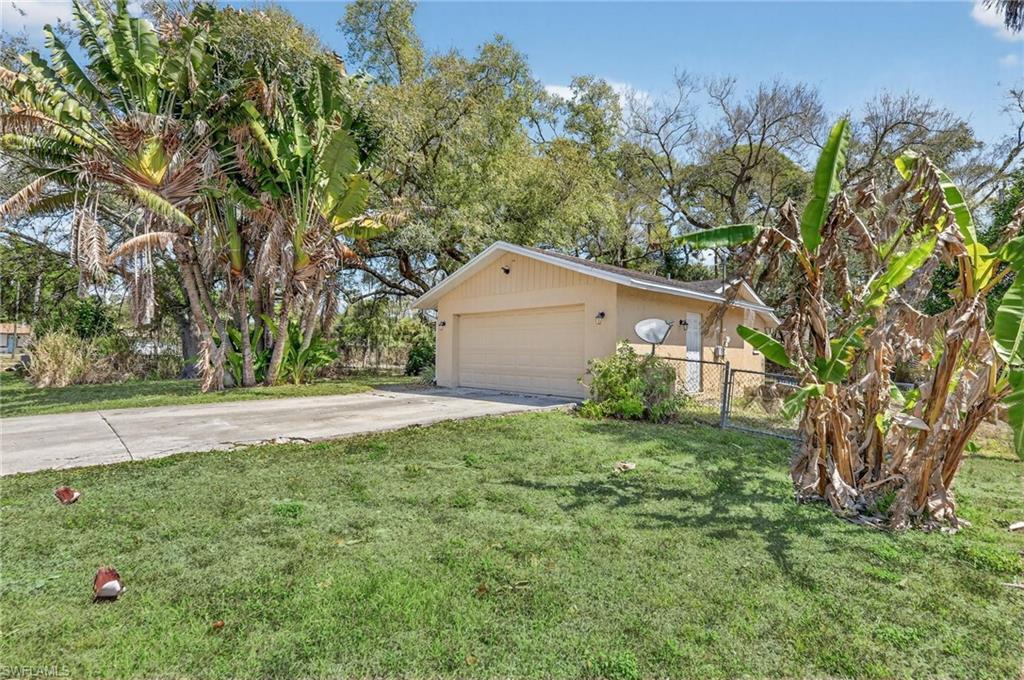 Image 4: View of front of home with driveway, stucco siding, and a gate