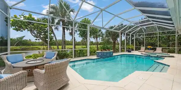 Image 2: Screened outdoor living area featuring a rectangular pool and integrated spa