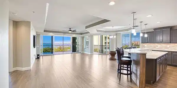 Image 4: Kitchen featuring a tray ceiling, a breakfast bar area, open floor plan, dark wood-type flooring, and light stone countertops