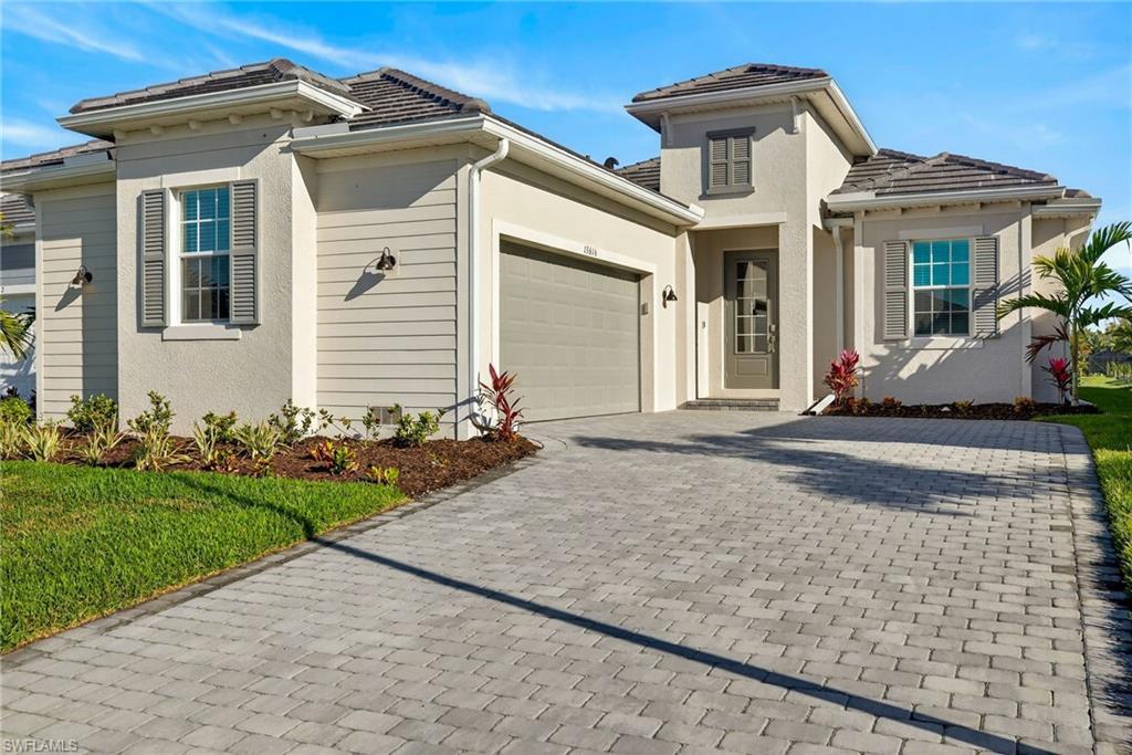 Image 3: View of front of house featuring decorative driveway, an attached garage, stucco siding, and a tiled roof