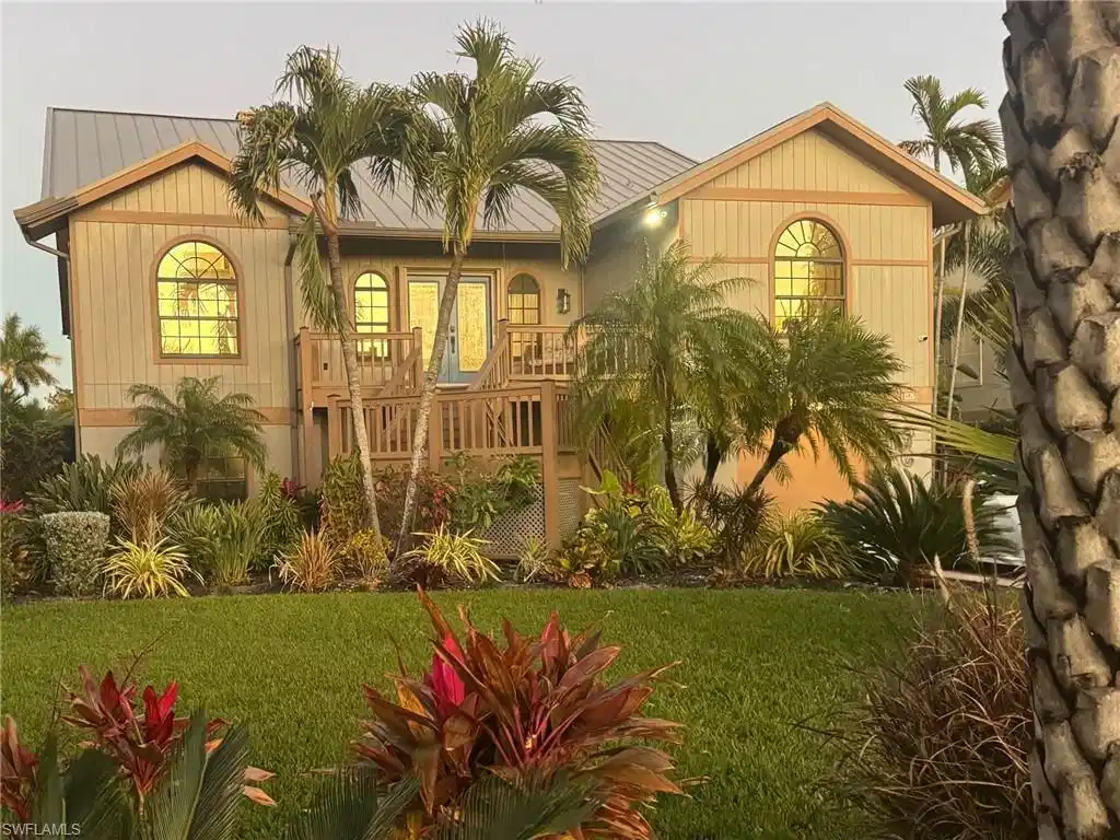 Image 1: View of front facade with a balcony, a front lawn, and a metal roof