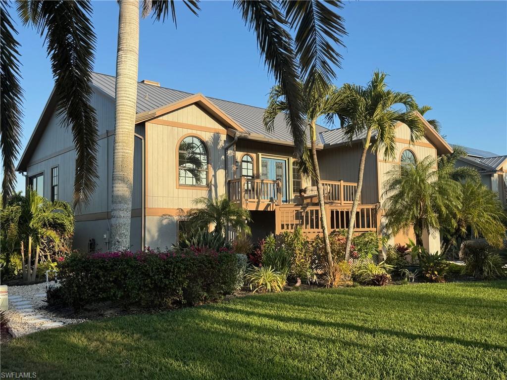 Image 2: View of front facade featuring a wooden deck, a front yard, and a metal roof