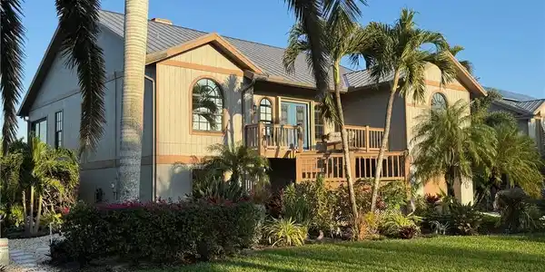 Image 2: View of front facade featuring a wooden deck, a front yard, and a metal roof
