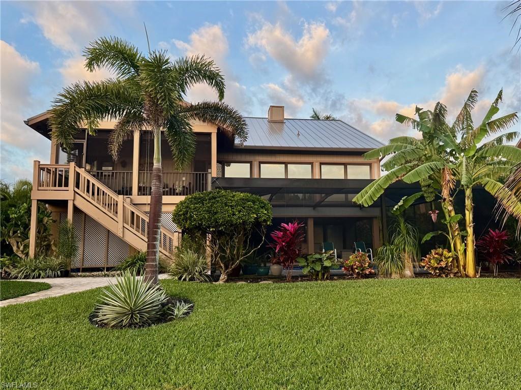 Image 3: Rear view of house with a yard, a metal roof, a deck, a sunroom, and a chimney