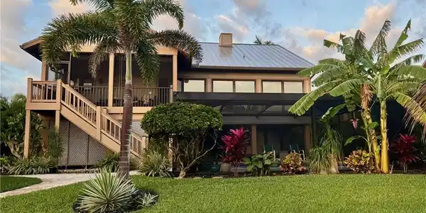 Image 3: Rear view of house with a yard, a metal roof, a deck, a sunroom, and a chimney