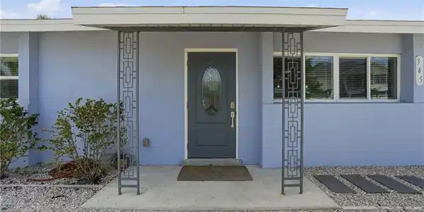 Image 3: Front entry featuring a covered porch with decorative metal columns, a dark gray oval-lite door.