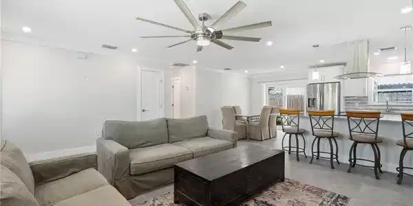 Image 4: Open-concept living space featuring a modern ceiling fan, recessed lighting, crown molding, and wood-finish tile flooring