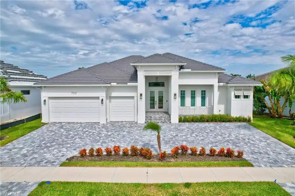 Image 1: Modern architectural home featuring a distinctive peaked roofline with charcoal gray shingles, crisp white exterior, and green accent doors