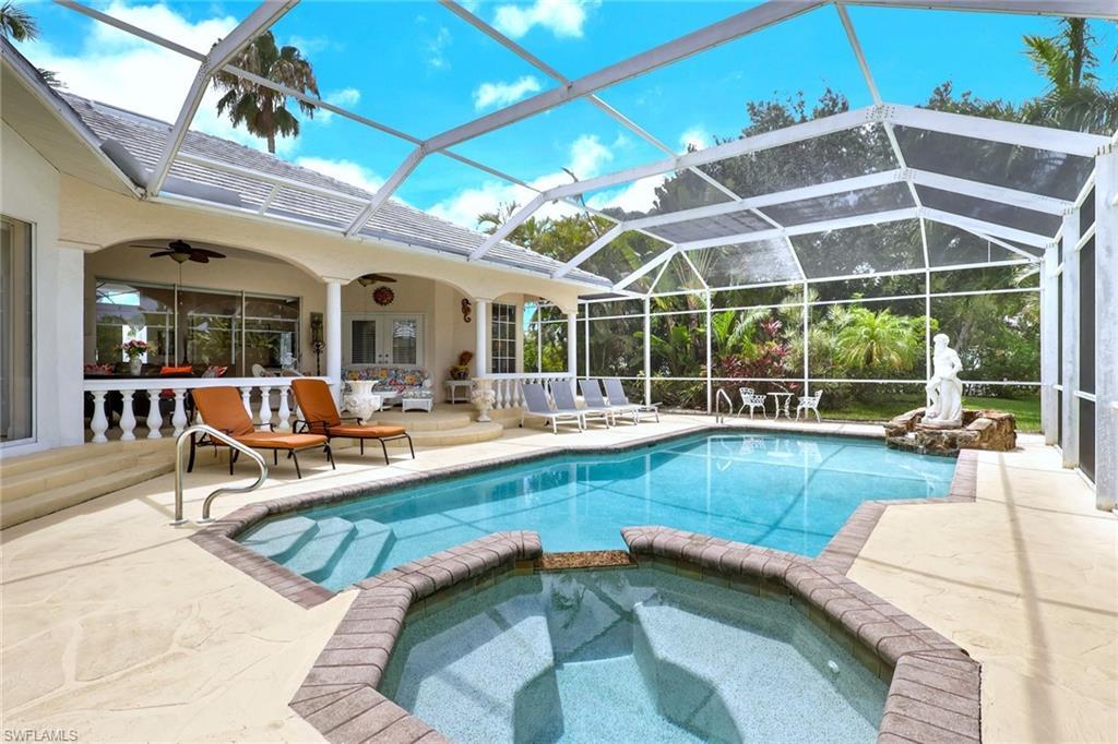 Image 3: Screen-enclosed pool area featuring a large swimming pool, integrated spa, and a rock waterfall feature