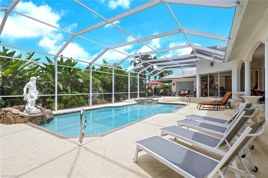Image 4: Screened-in pool area featuring a rectangular pool, integrated spa, and expansive paved deck