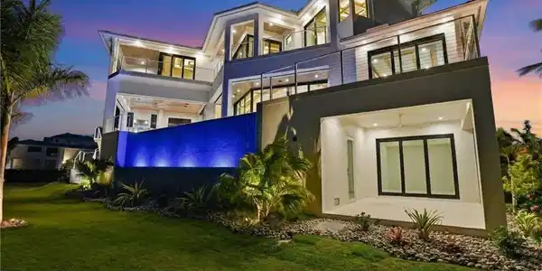 Image 4: Rear view of house with stucco siding, a balcony, and a lawn - Virtually Edited Image