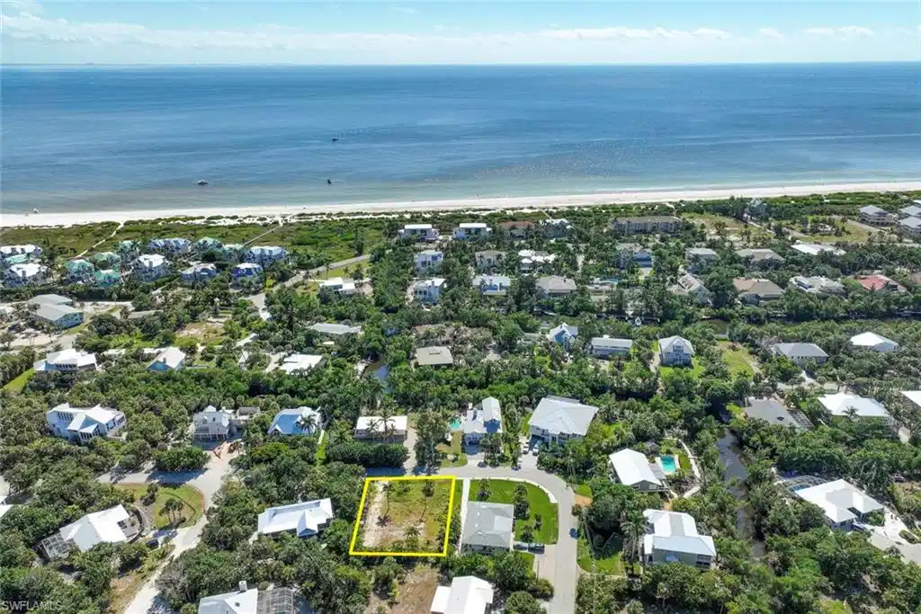 Image 1: Aerial perspective of suburban area with waterfront with a beach and property boundaries highlighted