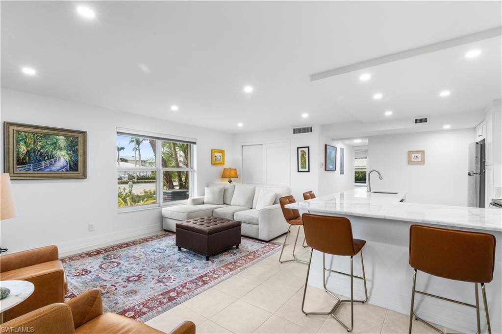 Image 4: Spacious living room / kitchen area. Laundry is located in closet behind couch.  Furnishings included. Canned lighting and windows make this condo light and bright!  Marble countertops.