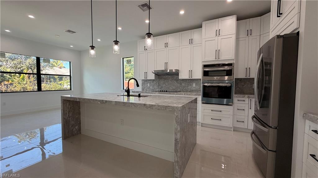 Image 3: Kitchen with appliances with stainless steel finishes, light stone countertops, decorative backsplash, pendant lighting, and recessed lighting