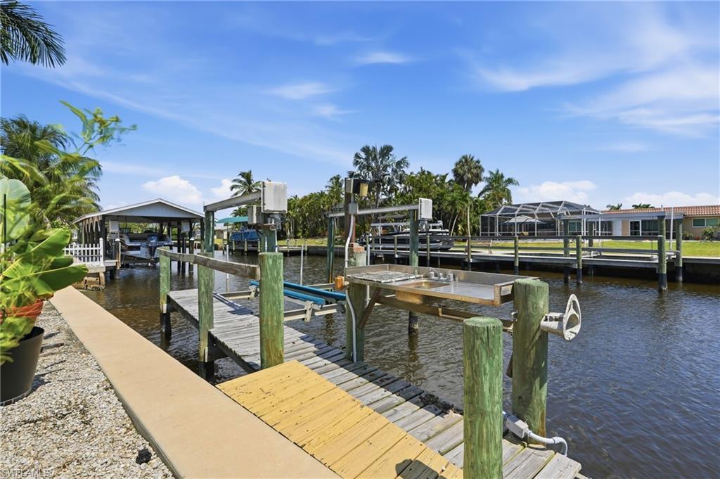 Image 4: Waterfront property with a private dock featuring a boat lift and a built-in cleaning station