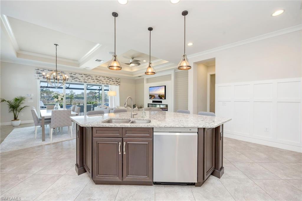 Image 4: Kitchen features wainscoting panels, large island with a breakfast bar, granite counters, recessed, under counter and pendant lighting