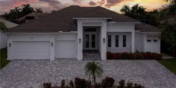 Image 3: Modern white stucco residence featuring a hipped tile roof, three-car garage with panel doors, and a circular driveway finished in permeable pavers
