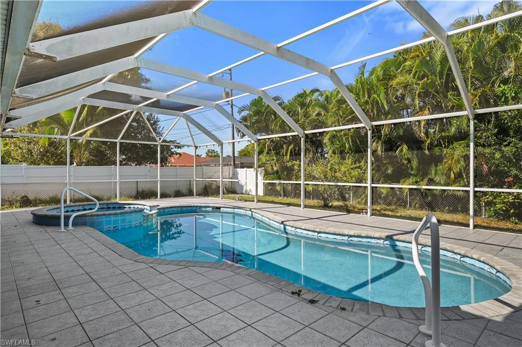 Image 2: View of swimming pool featuring glass enclosure, a pool with connected hot tub, a patio area, and a sunroom