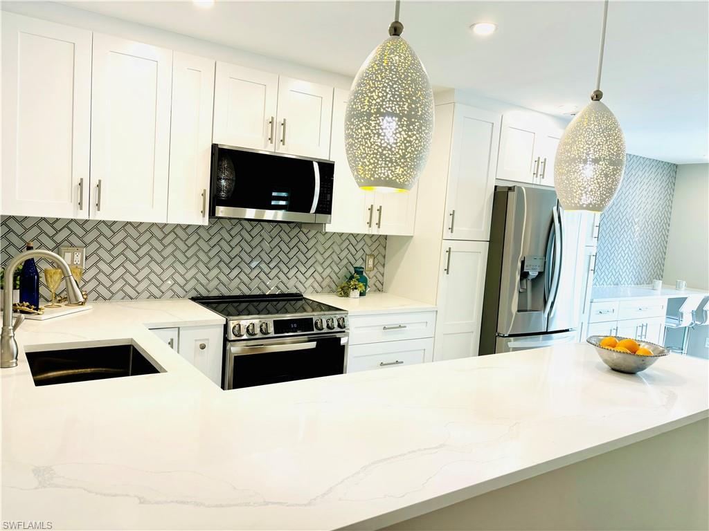 Image 2: Kitchen featuring all  new stainless appliances, white cabinetry, light wood-style tile floors, granite  countertops, and pendant lighting