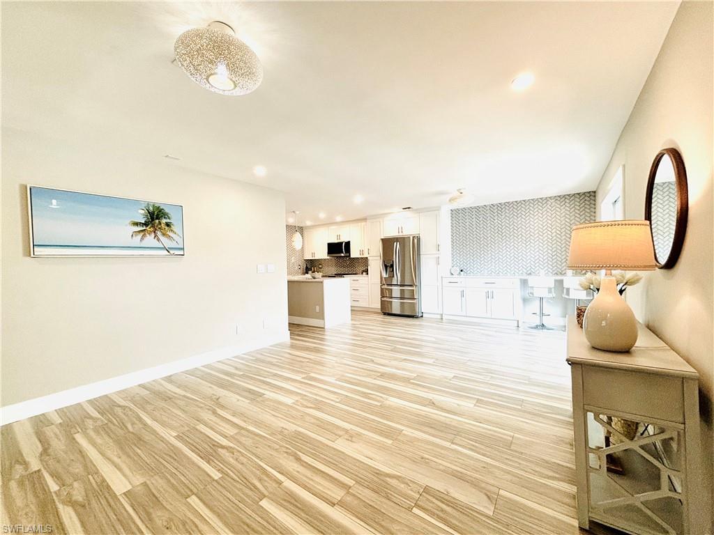 Image 3: Open living area featuring light wood-style tile flooring throughout, recessed lighting