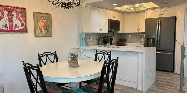 Image 4: Open-concept kitchen featuring white cabinetry, a large refrigerator, and a kitchen island with seating