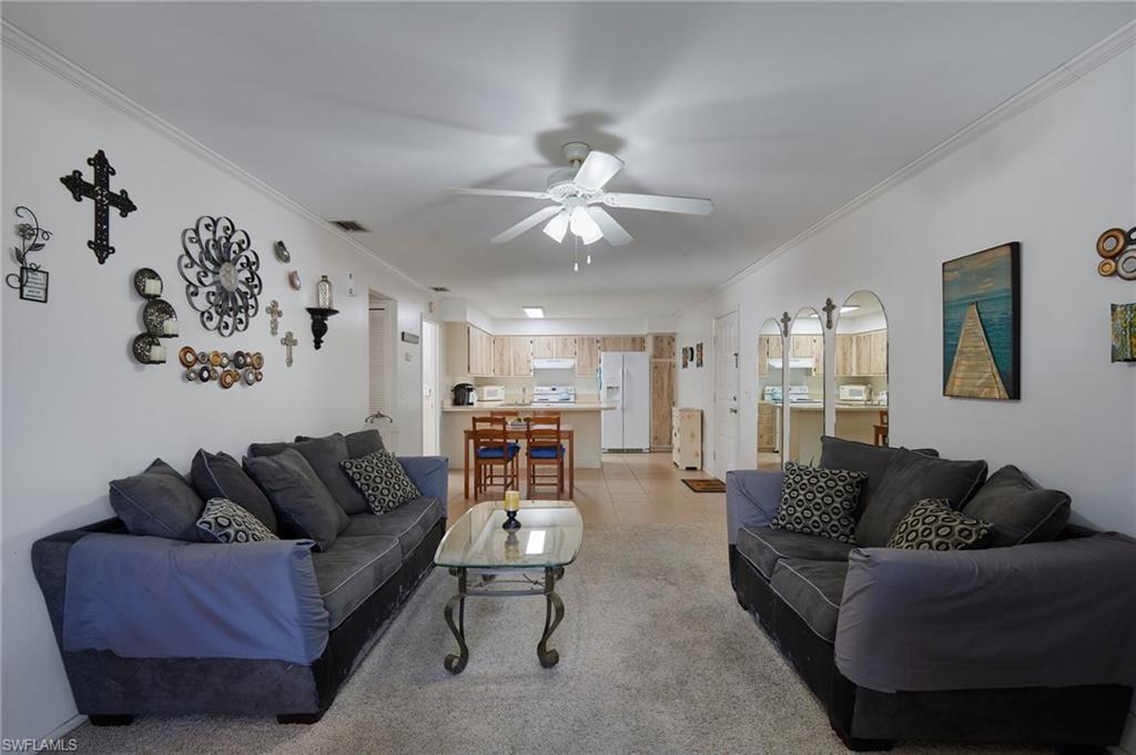 Image 4: Living area with ornamental molding, light tile patterned floors, arched walkways, and a ceiling fan