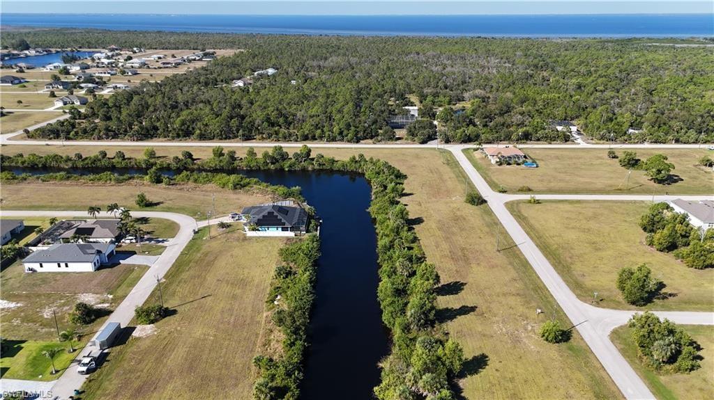 Image 2: Aerial overview of property's location with a nearby body of water and a forest