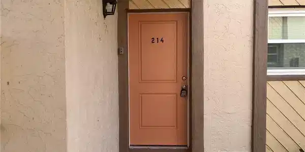 Image 2: Entry door featuring a panel design, a numeric address, and a wall-mounted exterior light fixture