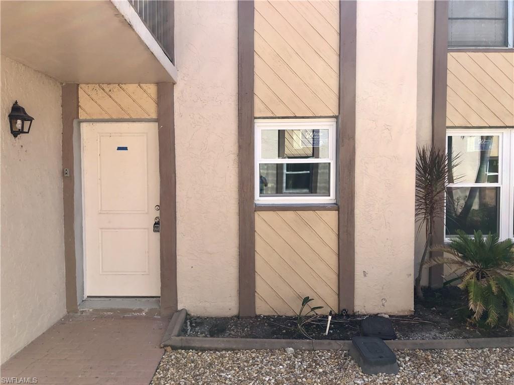 Image 3: Exterior entryway featuring a paneled door, wall-mounted light fixture, and textured siding details