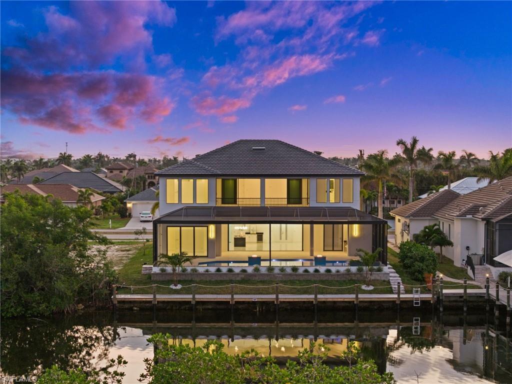 Image 2: Back house at dusk featuring a water view and a yard