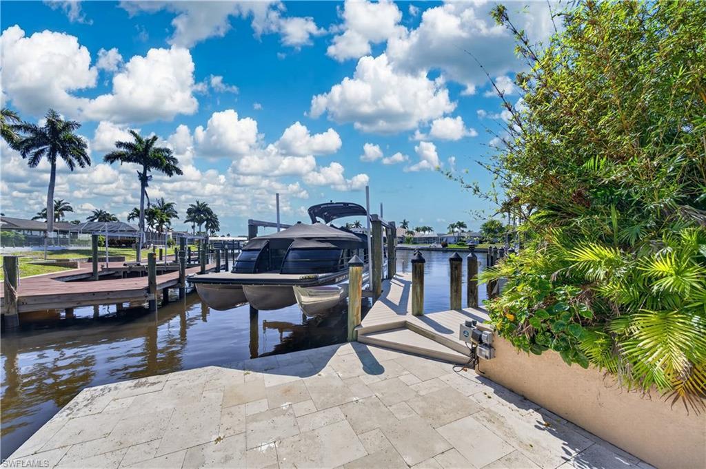 Image 2: Waterfront property featuring a private dock with a boat lift, stone paver patio, and lush landscaping